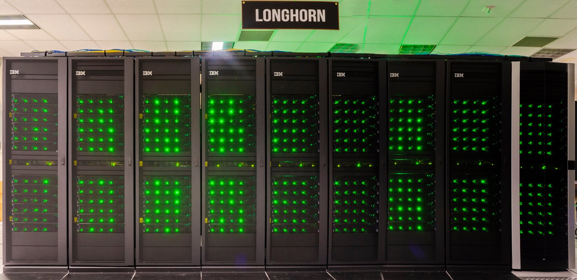 Front view of the tall, black racks of compute nodes in the former Longhorn subsystem of TACC Frontera. Each node is marked by a row of 4 green lights, possibly indicating the status of the 4 Tesla V100s hosted by the node.